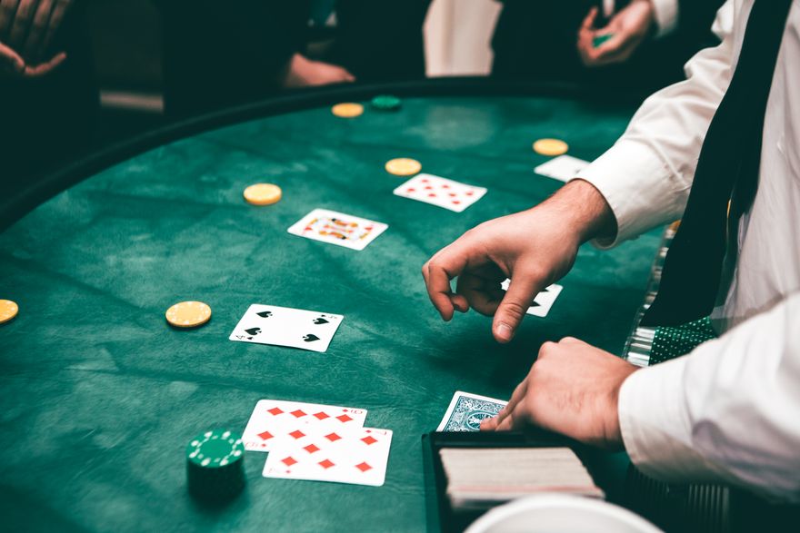 Chip poker bertumpuk di samping kartu remi di atas meja hijau